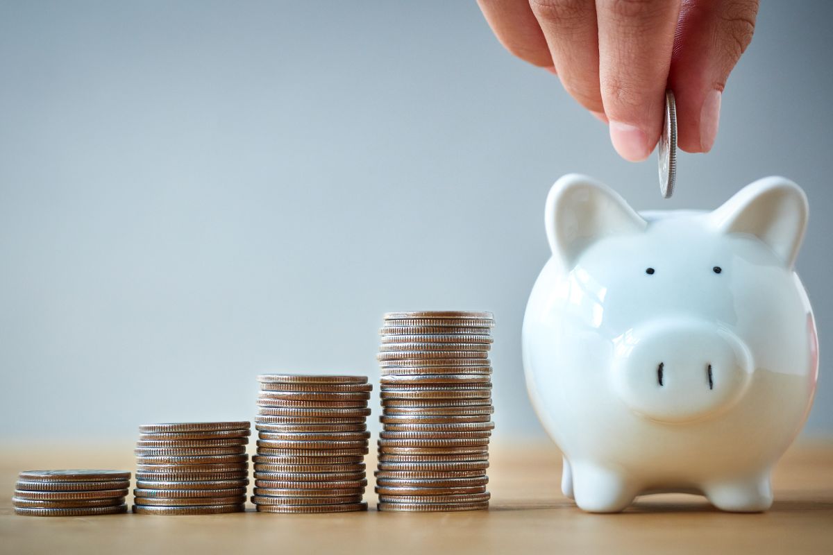 The photo shows a man's hand saving money.