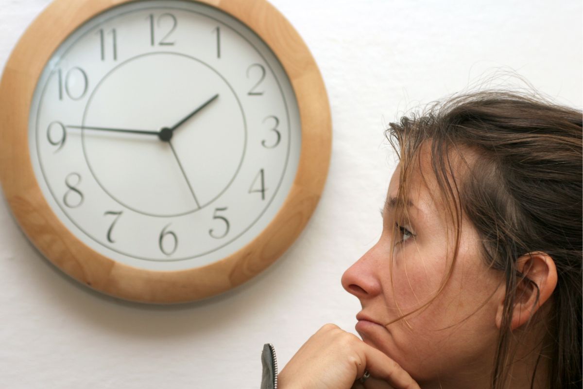 A photo shows a woman looking at the clock.