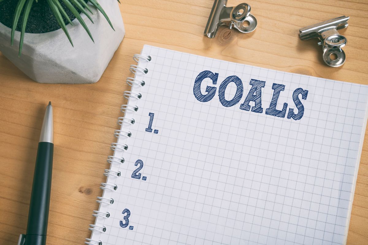 The picture shows a pen and a notebook with goal wording.