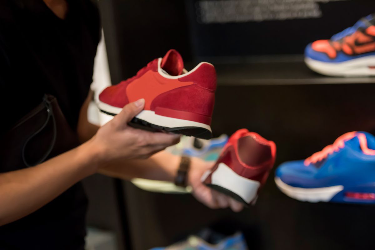 The photo shows a man's hand buying a new pair of shoes.
