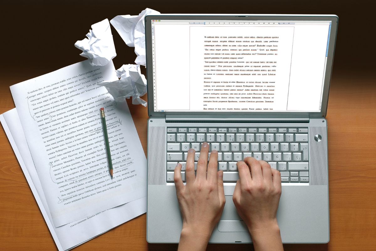An image of a woman's hand typing on a laptop.