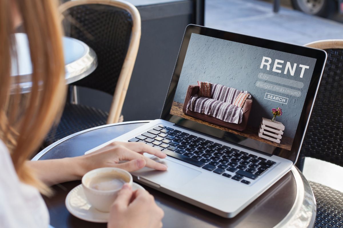 The image shows a woman listing a rental online.