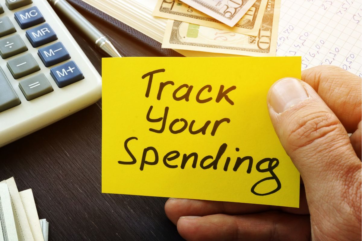 Picture of a man's hand holding a paper with Track your Spending wording.