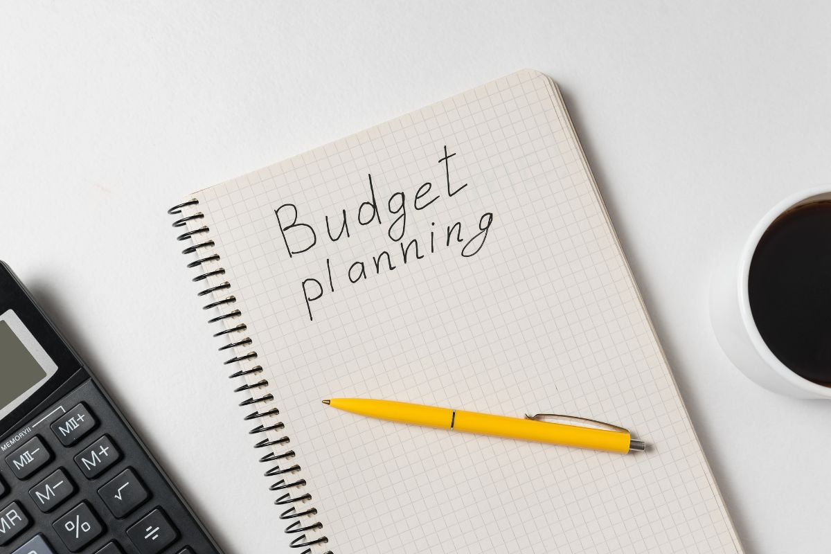 The picture of a calculator and a notebook with budget planning wording.