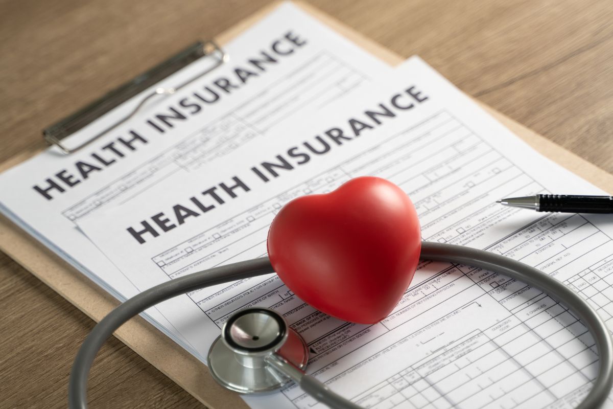 The picture shows a stethoscope and health insurance forms.