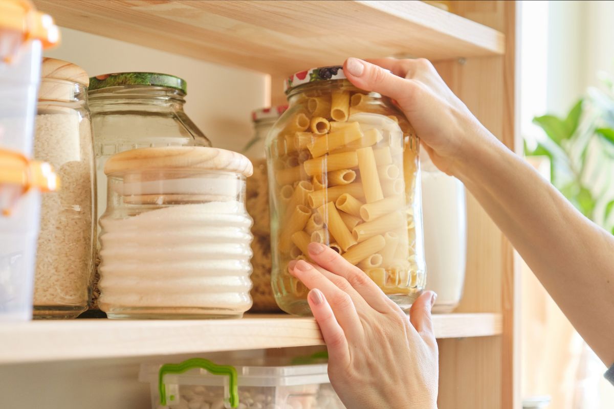 The image shows a woman's hand organizing the pantry.