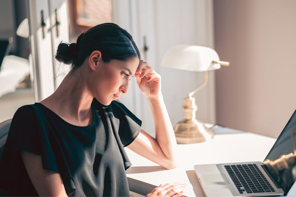 The photo of a woman wondering while using a laptop.
