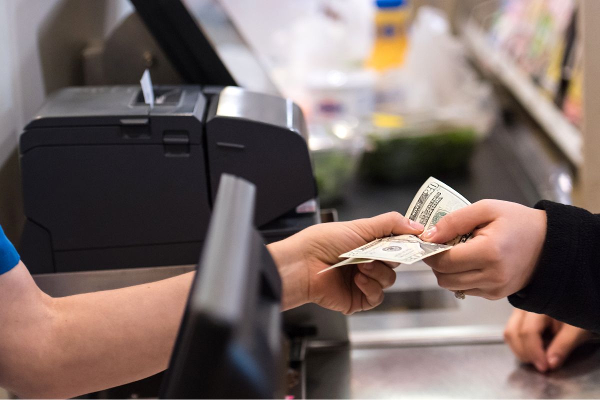 The photo shows a woman paying in cash.