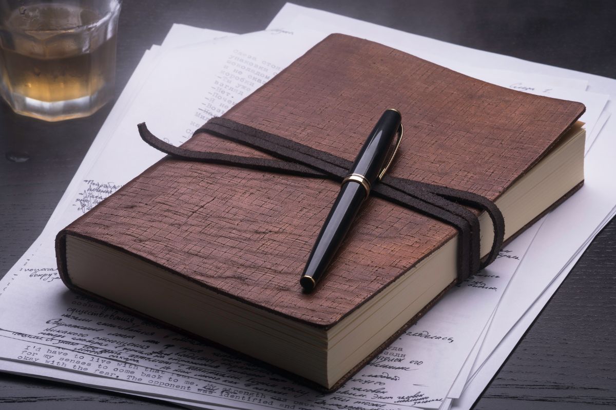 The image shows a pen and a journal notebook.