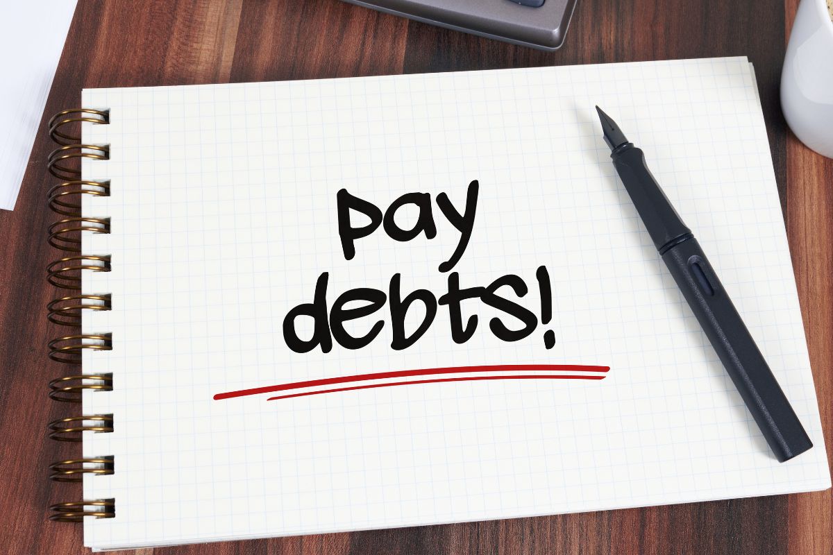 An image of a pen and a notebook with pay debts.