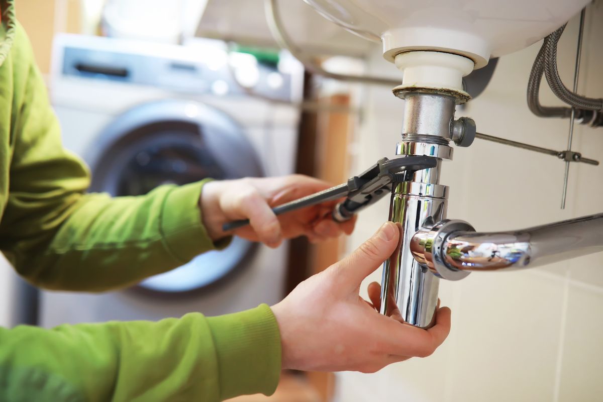 The image shows a man fixing a pipe.