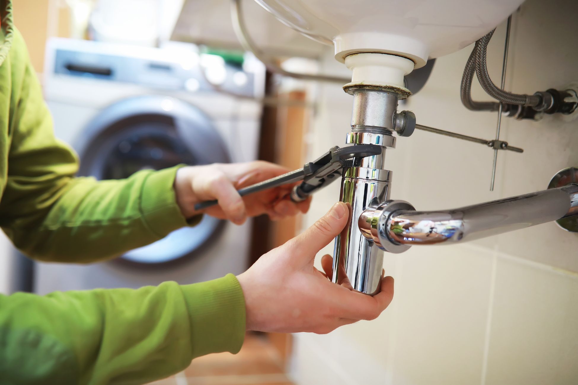 The picture shows a man's hand fixing the plumber referring to DIY home repairs can save hundreds or even thousands of dollars.