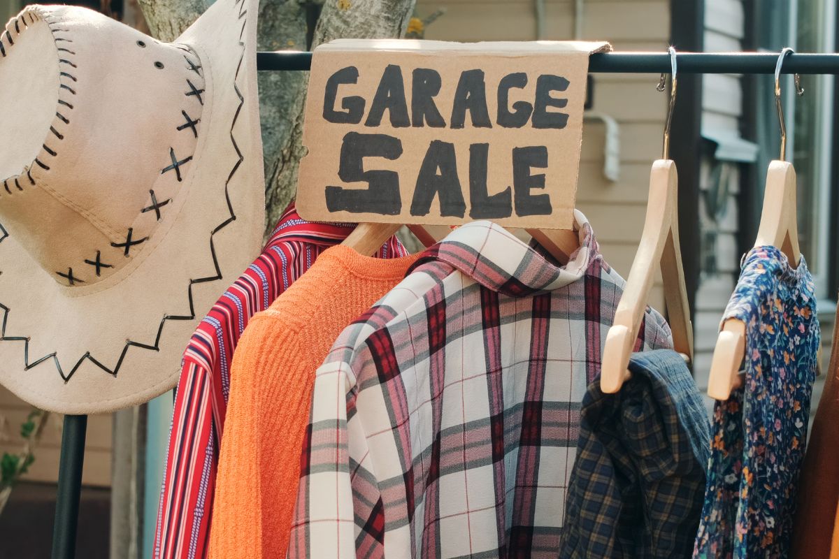The picture shows clothes and a board with a garage sale wording.