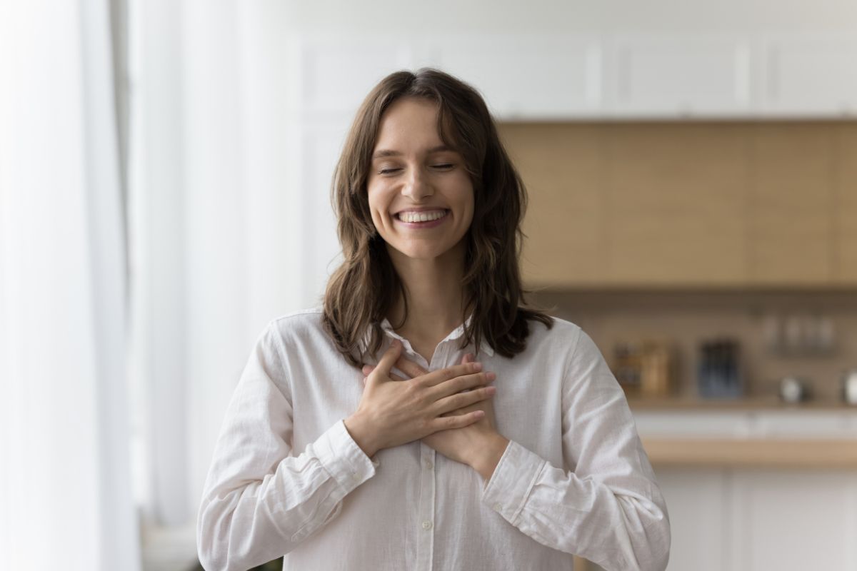 The photo tells about a girl placing her hands on her chest which means to practice contentment and gratitude helps shift focus to saving for what truly matters.