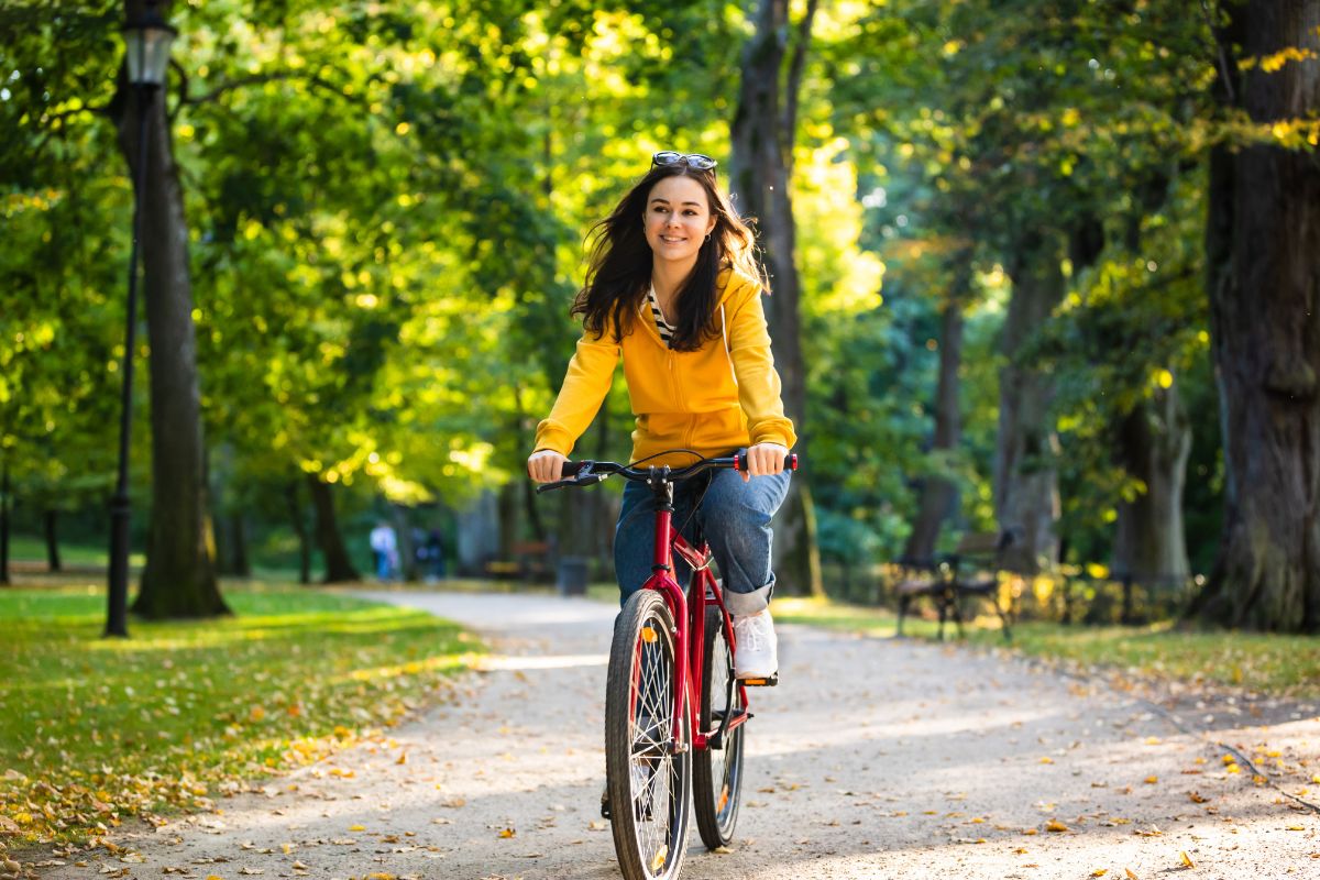 The picture of a grid using a bike at the shady trees street refers to riding bikes around your neighborhood is a good way to stay active and enjoy a no-spend weekend.