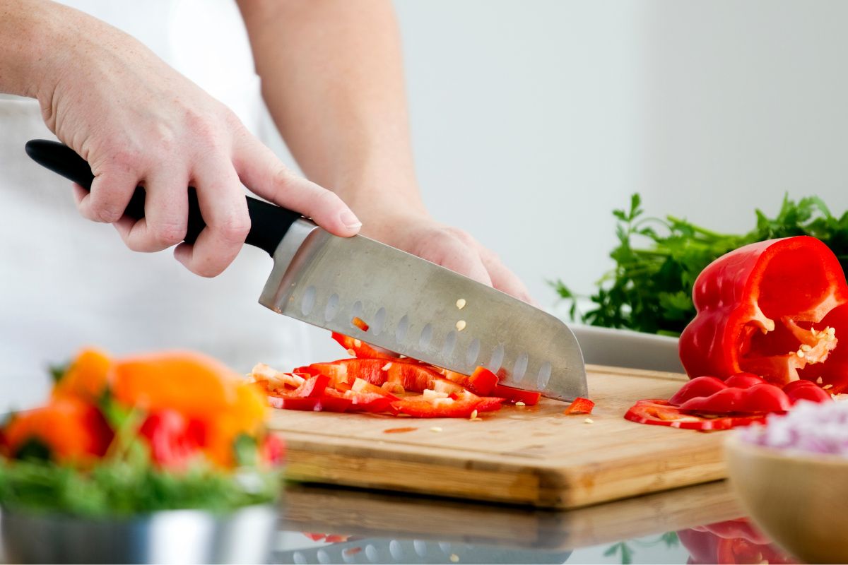 Picture of a woman's hand slicing ingredients.