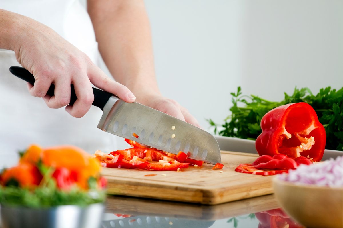 The photo shows ingredients in the bowl and a girl slicing a bell pepper which means cooking a new recipe is a great way to use up ingredients.