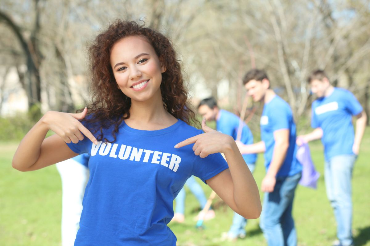 The picture tells about a group of people cleaning the area and a girl pointing her shirt which means that volunteering at a local charity is a meaningful way to spend a no-spend weekend. 