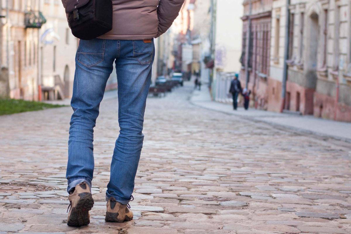 The photo shows a man walking in the street referring to exploring a new pat of town keeps the trip free and lets you notice things you might usually miss.