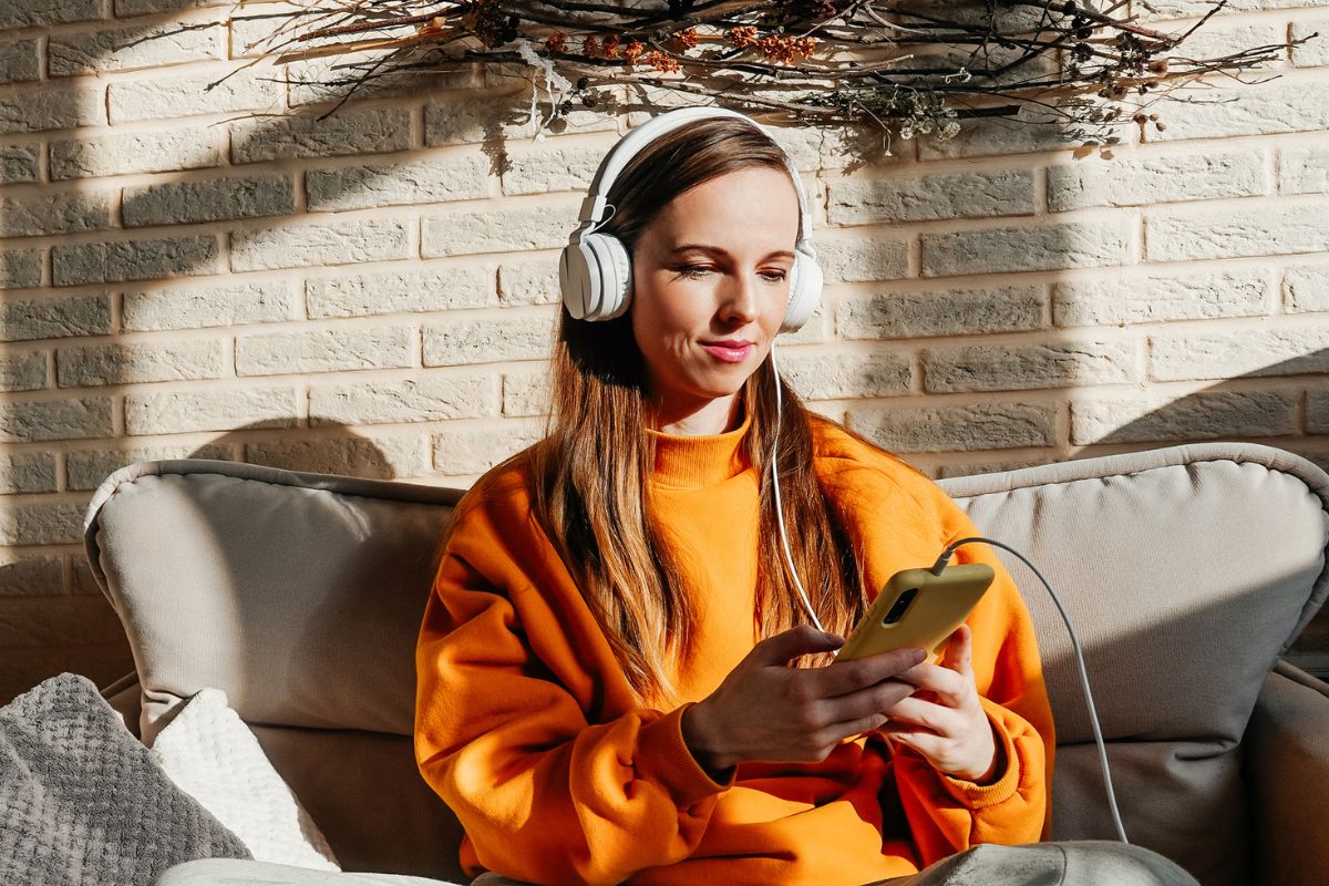 The picture tells about a girl using a phone and a headphone referring to listening to podcasts for inspiration as an easy way to pass the time for free.