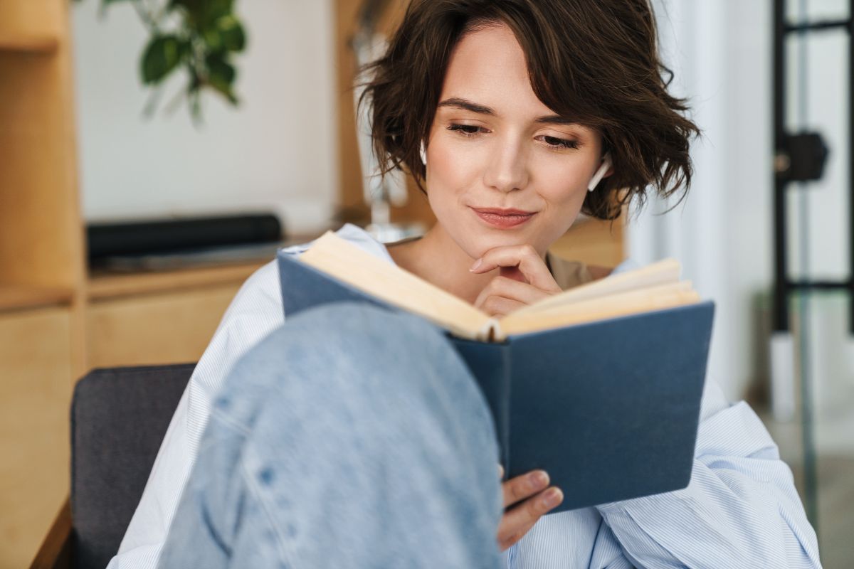 The picture shows a girl reading a book while sitting on a chair indicating that continuously educating yourself on finances helps build wealth over time and make better financial decisions.