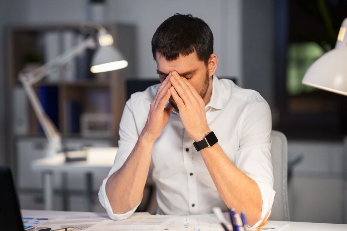 The photo tells about papers on the table, a lamp, and a frustrated man referring to taking calculated risks and embracing failure, learning from it helps people succeed and build wealth.