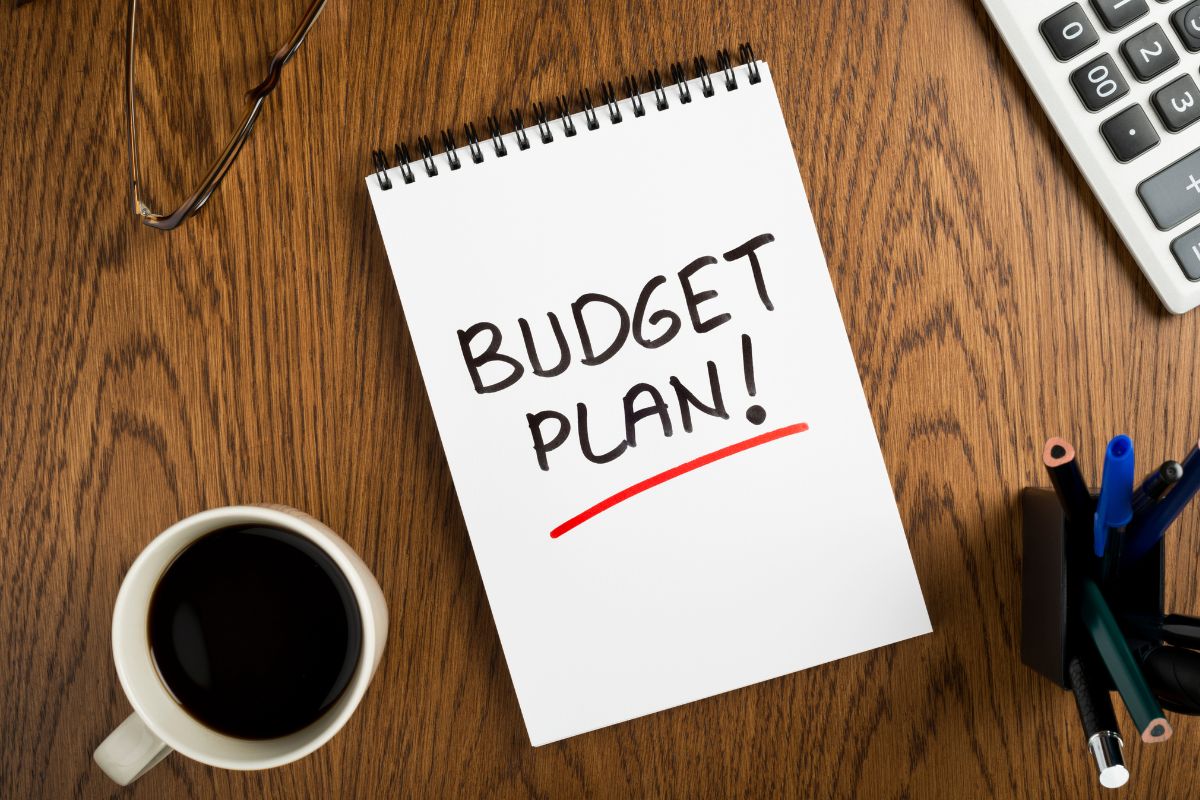Image of a coffee and a notebook with budget plan wording.