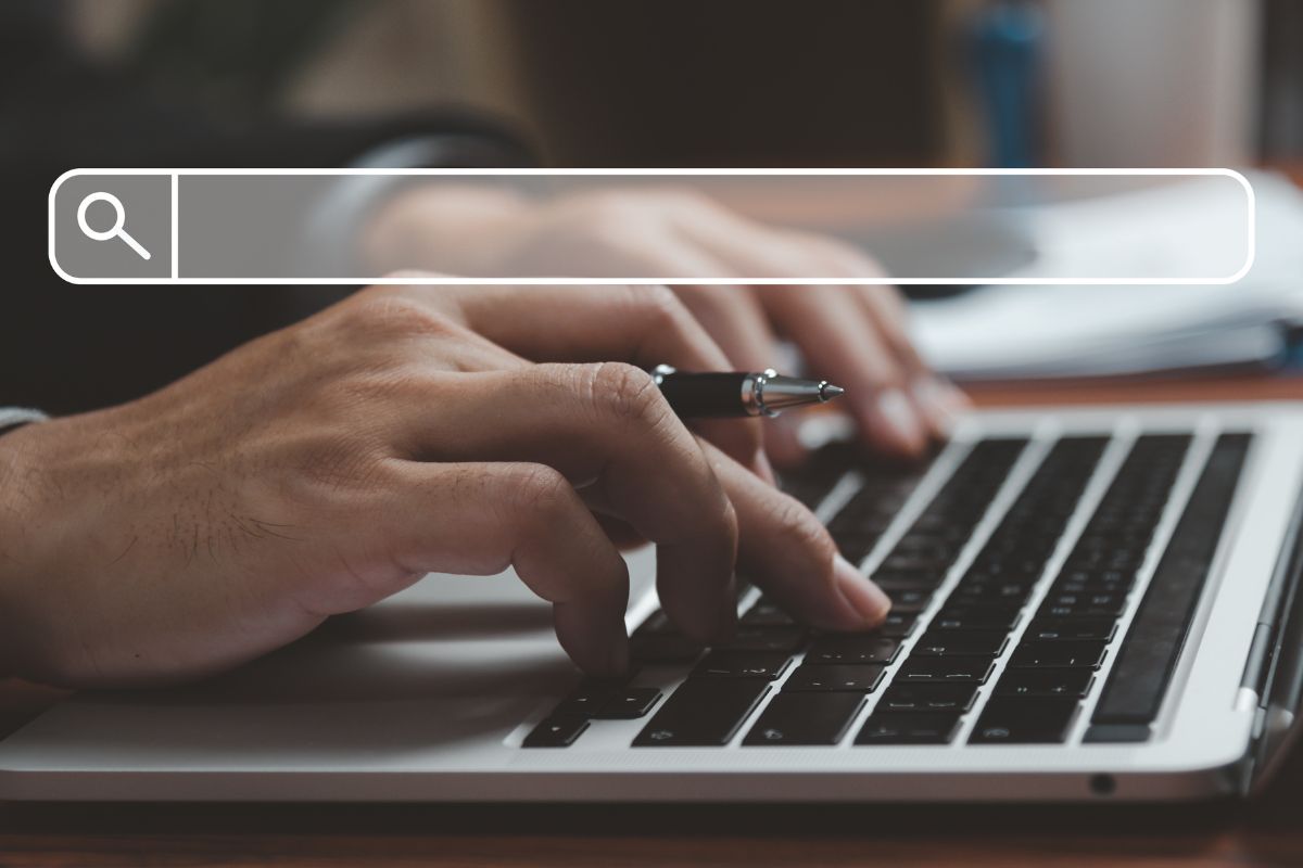 The image shows a man's hand using a laptop with a visual search icon referring to always looking for ways to increase efficiency and productivity means more time for things that grow wealth.