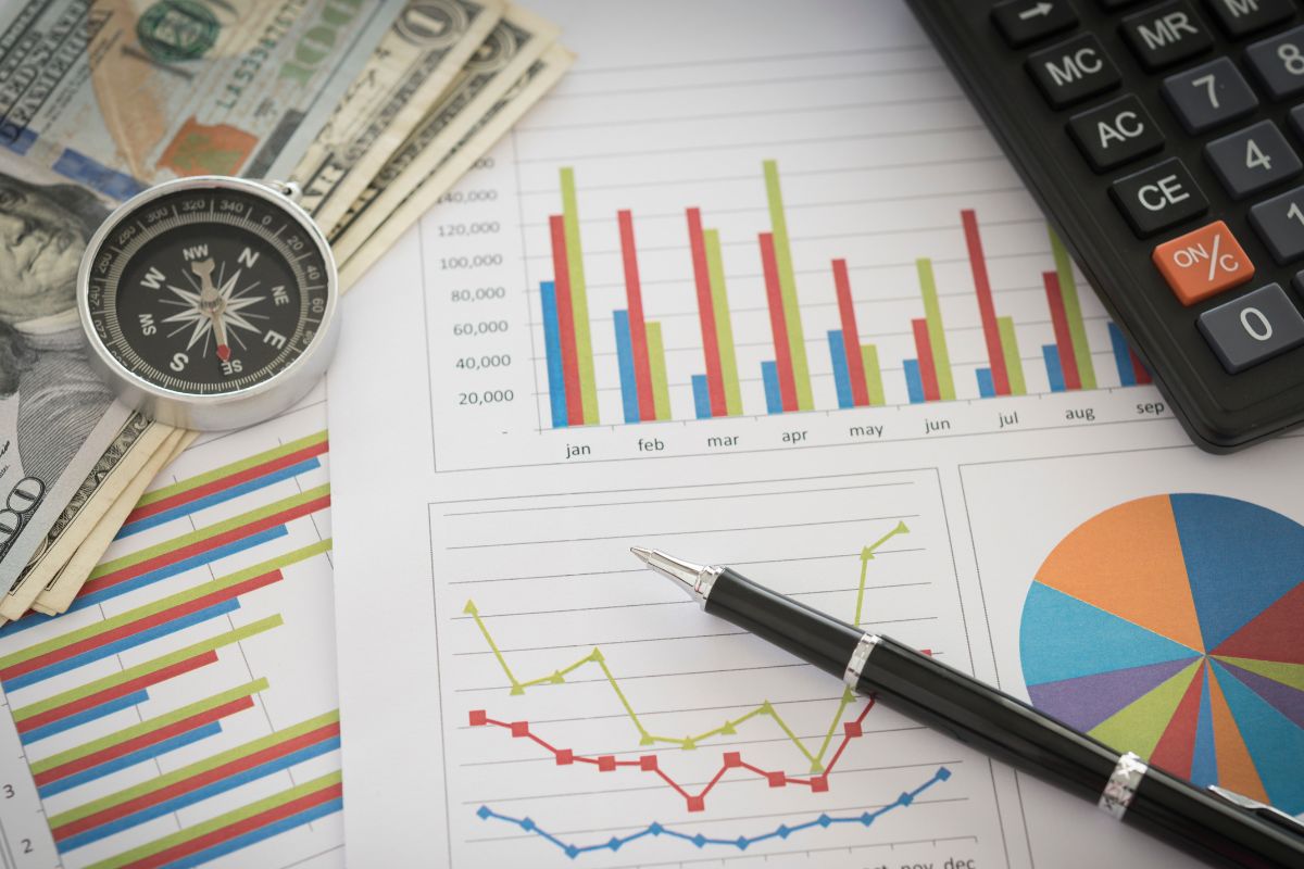 Image of money, a calculator, and paper with a financial progress report.