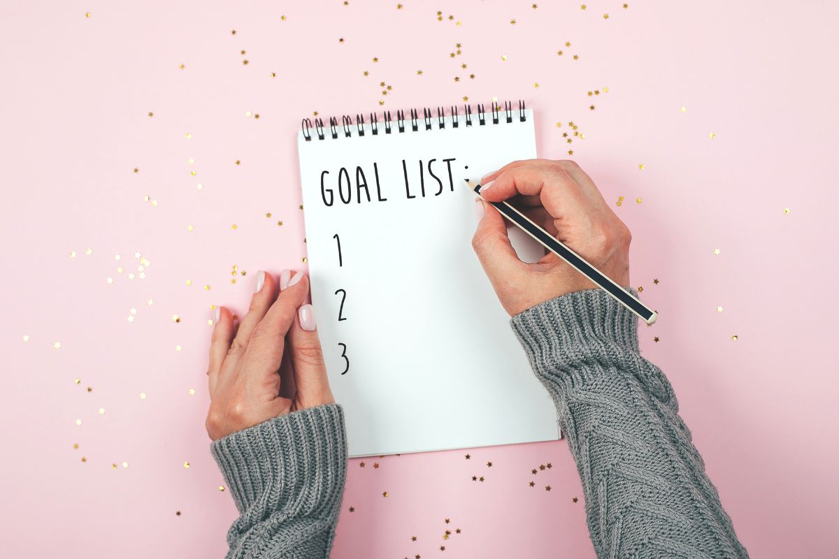 The picture shows a girl's hand and writing on the notebook referring to setting a clear goal for the pantry challenge helps you make better meal choices and resist unnecessary shopping.