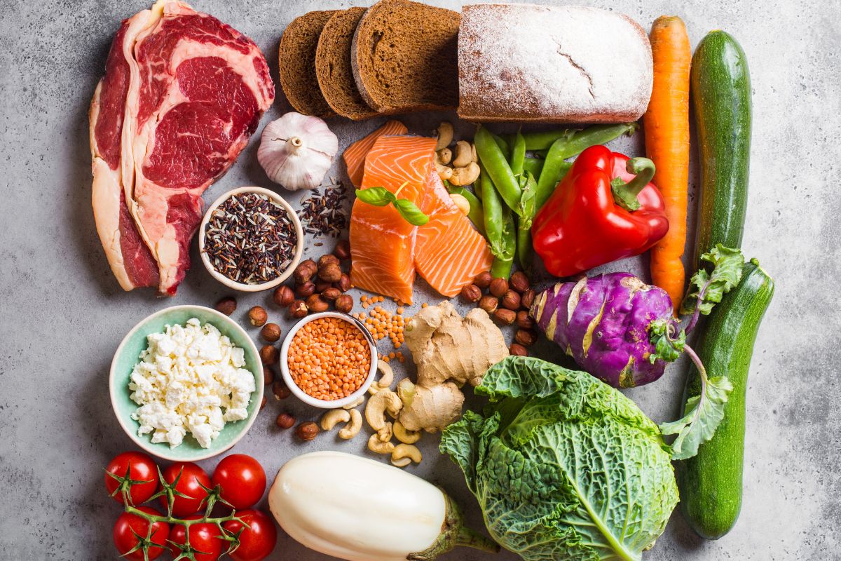 The picture shows meats, bread, vegetables, spices, and nuts, on the table referring to getting creative with ingredient substitutions keeps the meals interesting and avoids extra spending.