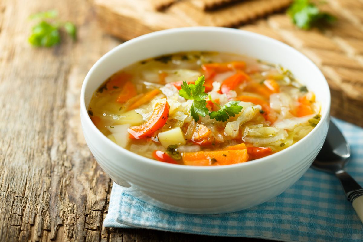The photo tells about a bowl with vegetables and a poon referring to making soups that let you mix and match ingredients together and an easy way to clear out your fridge while saving money on groceries.