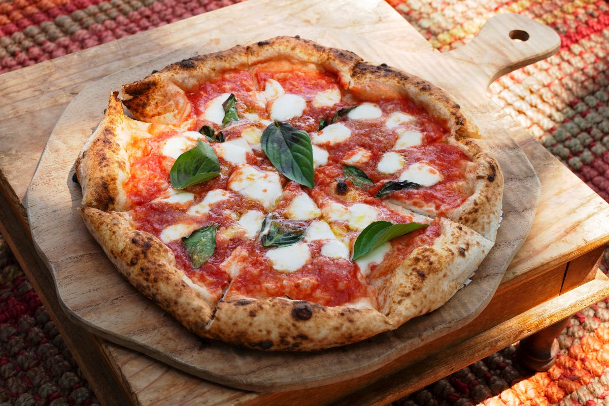 The image tells about a table and a wooden tray with a pizza referring to try themed night makes mealtime something to look forward to while saving money.