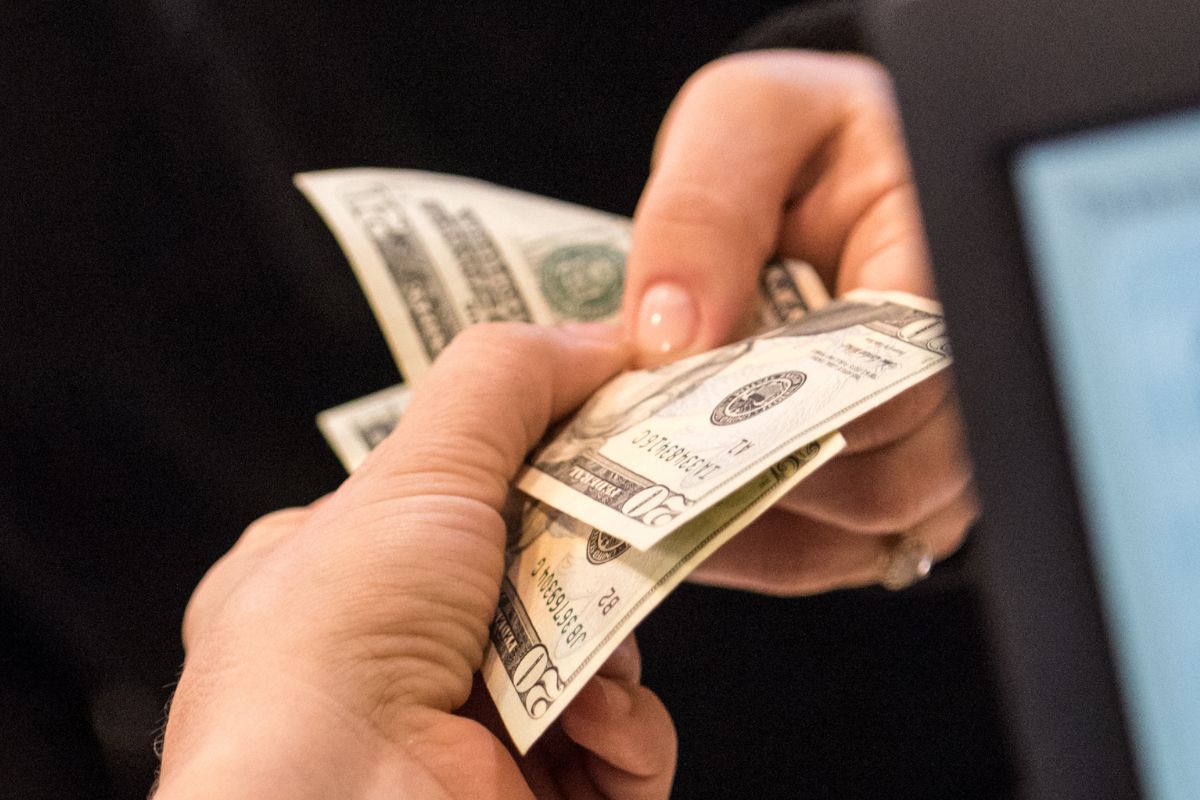 An image of a woman's hand paying in cash only.