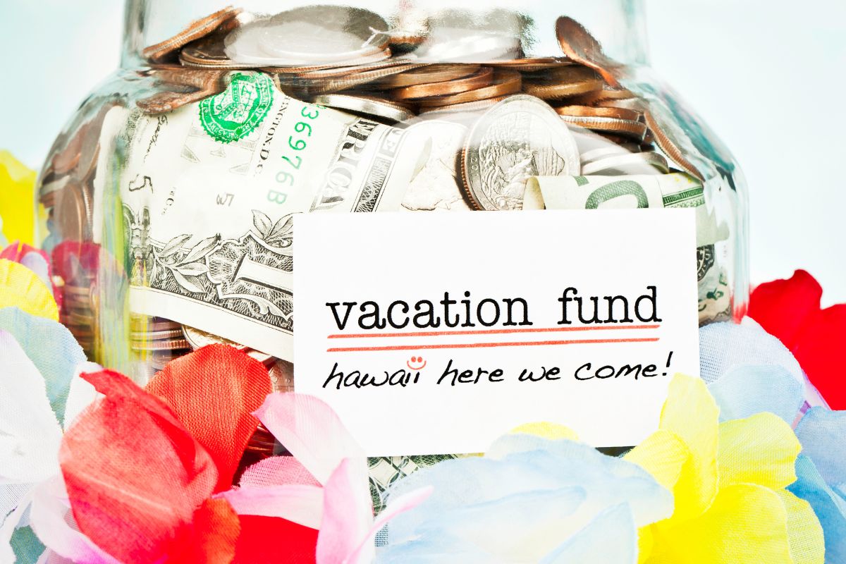 The picture of a jar filled with money and with vacation fund note.