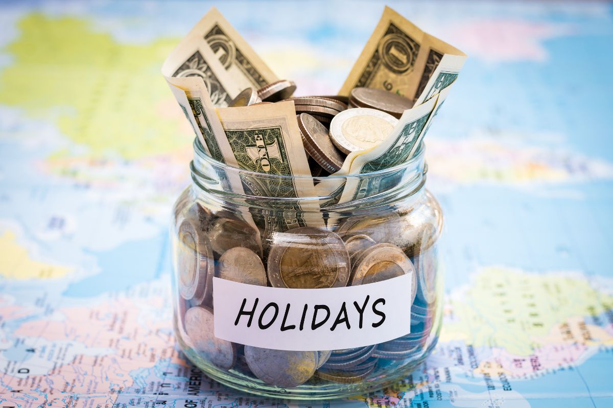 The picture shows a jar filled with money and with holiday note.