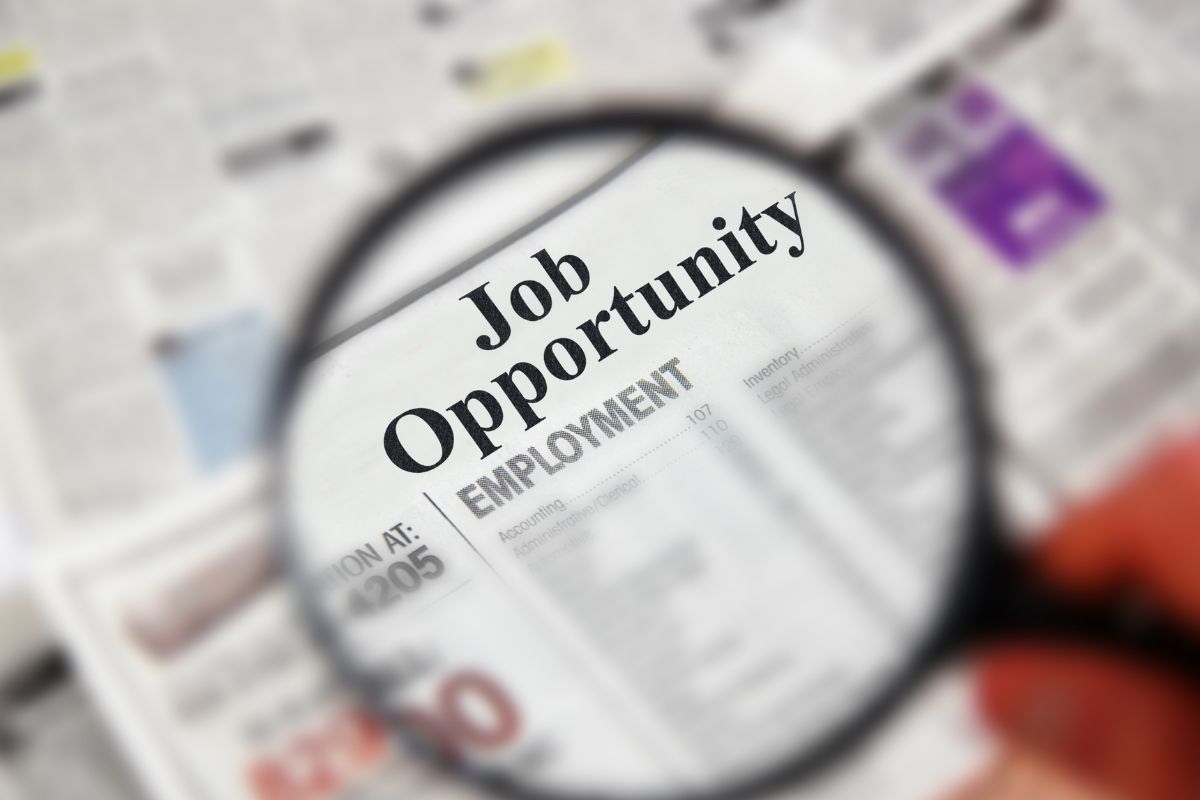 The photo tells about a newspaper and a man's hand holding a magnifying glass referring to expanded job opportunities making it easier to qualify for better jobs and move up in your career.