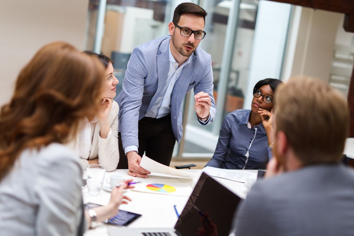 The photo shows papers, laptops, members, and a leading talking indicating that increasing earning power can significantly increase your income.