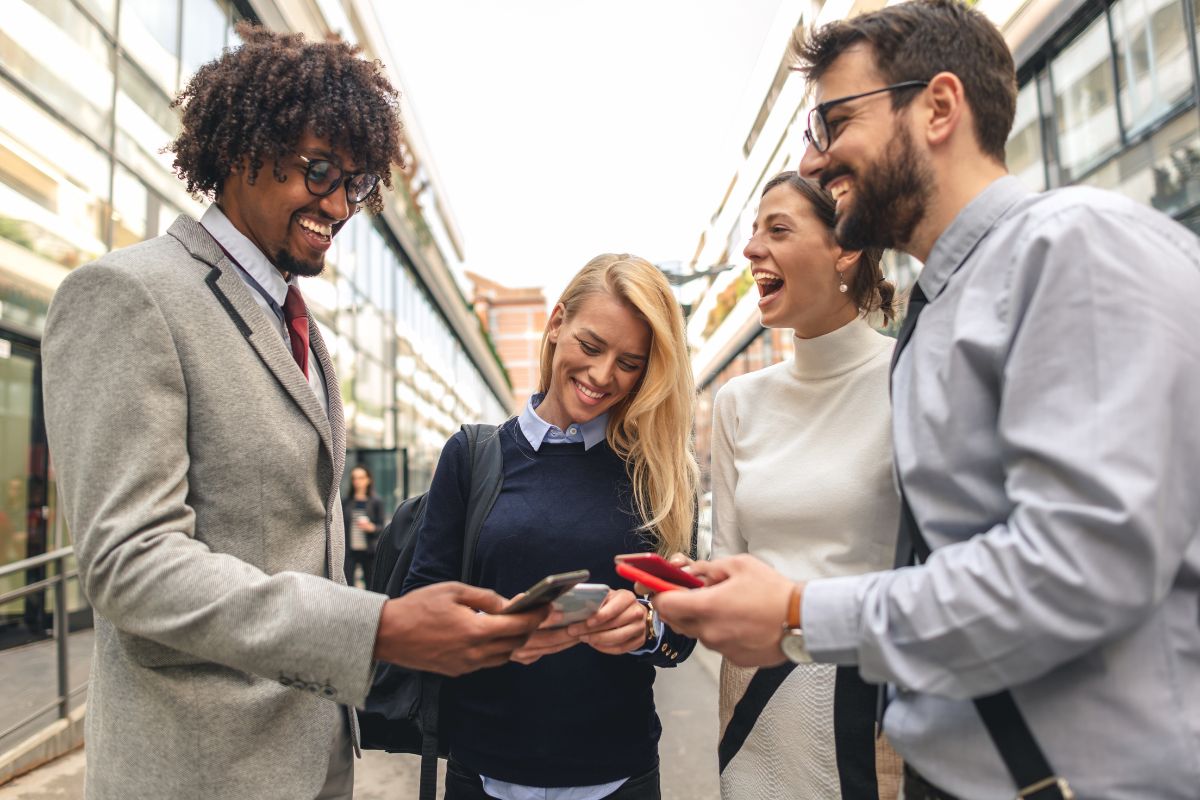 The picture shows a group of people talking together and using phones which means learning skills strengthens networking and collaboration opportunities and higher earnings.
