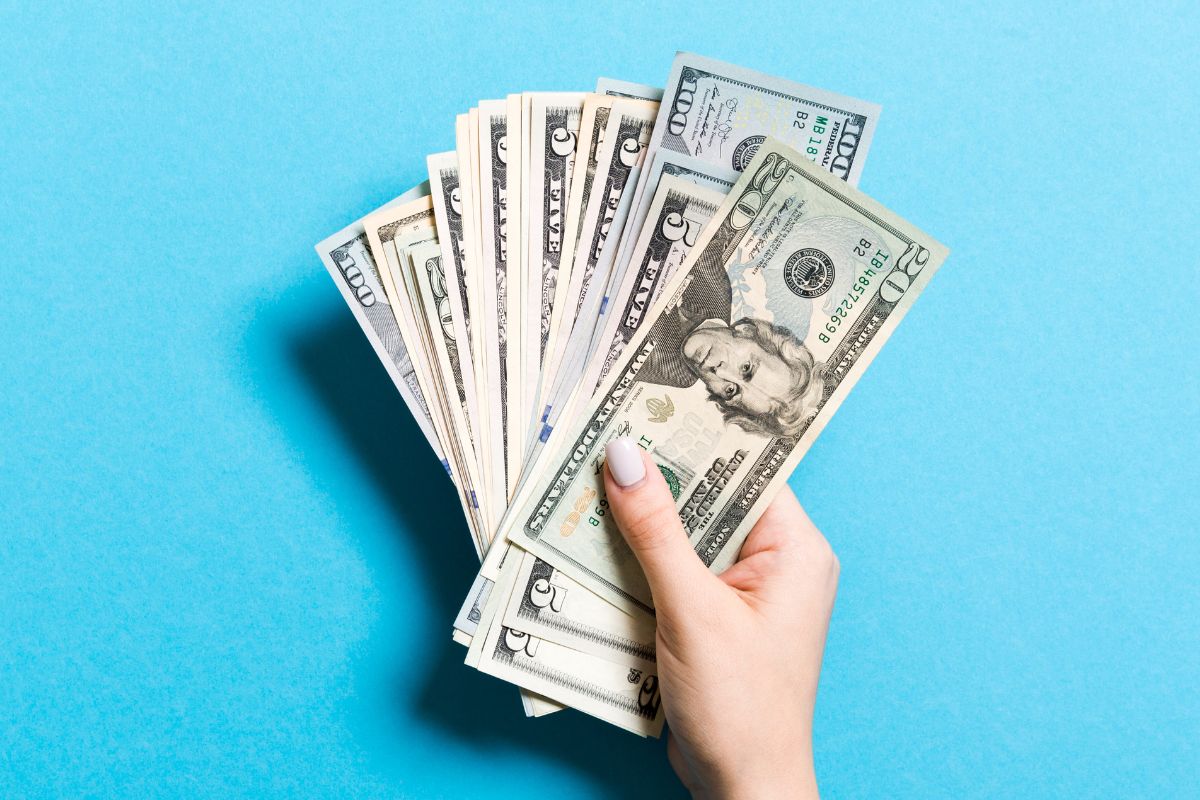 The picture tells about a girl's hand holding dollar bills which means only to carry large bills helps you avoid unnecessary spending and keep more money in your wallet.