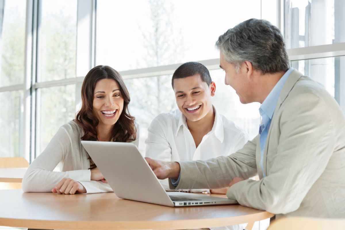 The photo tells about a couple and a man in a suit explaining the content on the laptop indicating that valuable skills leverage to start a high-income consulting can turn your knowledge into a well-paying career.