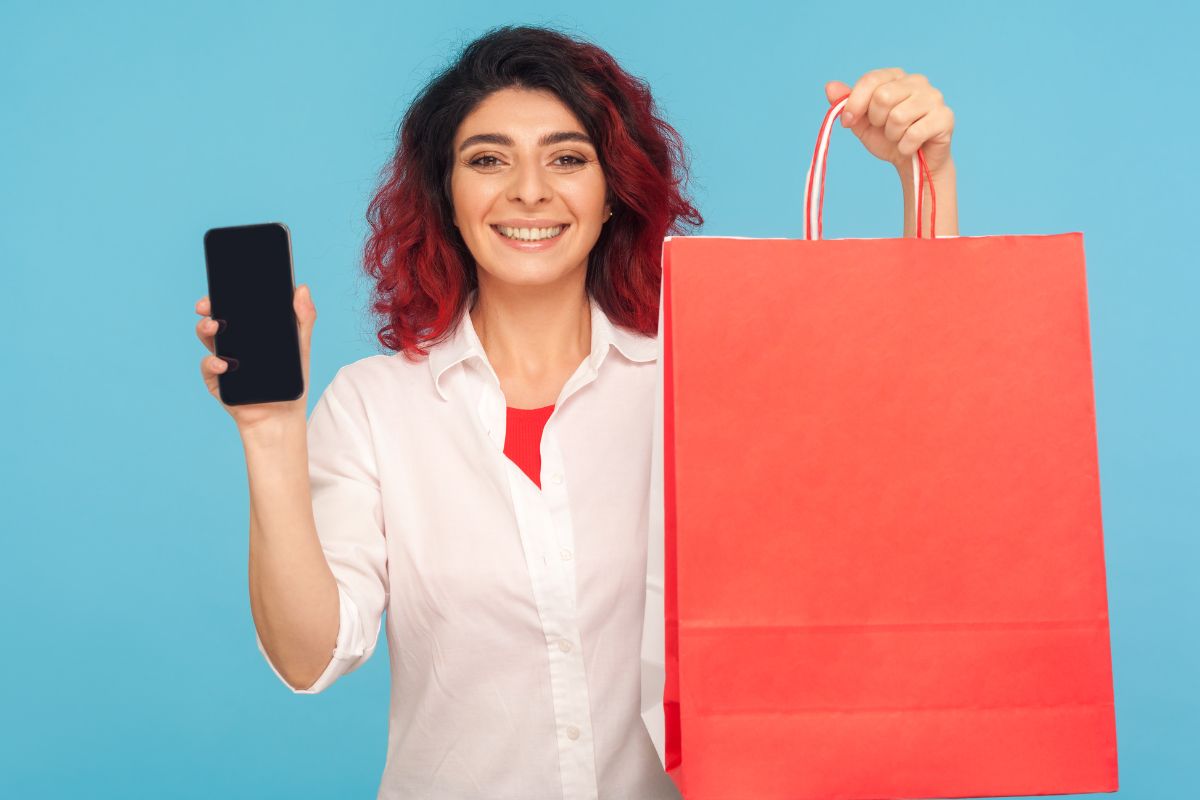 The photo shows a woman holding a phone and a shopping bag.