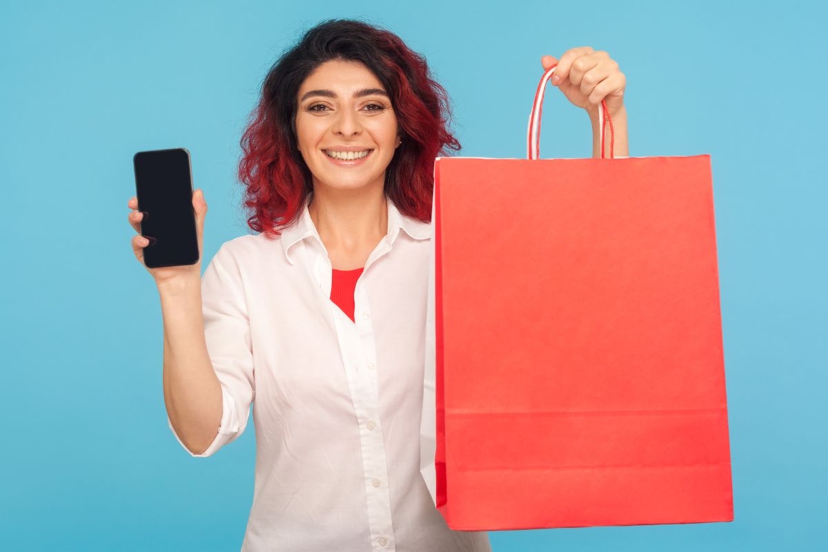 The image tells about a girl holding shopping bags and a phone which refers to round-up transactions as an easy way to build a financial cushion.