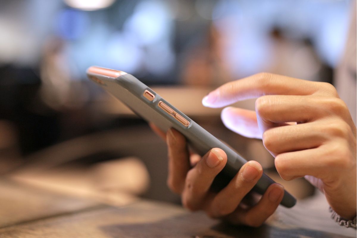 The picture tells about a girl's hand using a phone referring to unfollowing influencers who promote spending reduce the urge to keep up with trends and make unnecessary purchases.