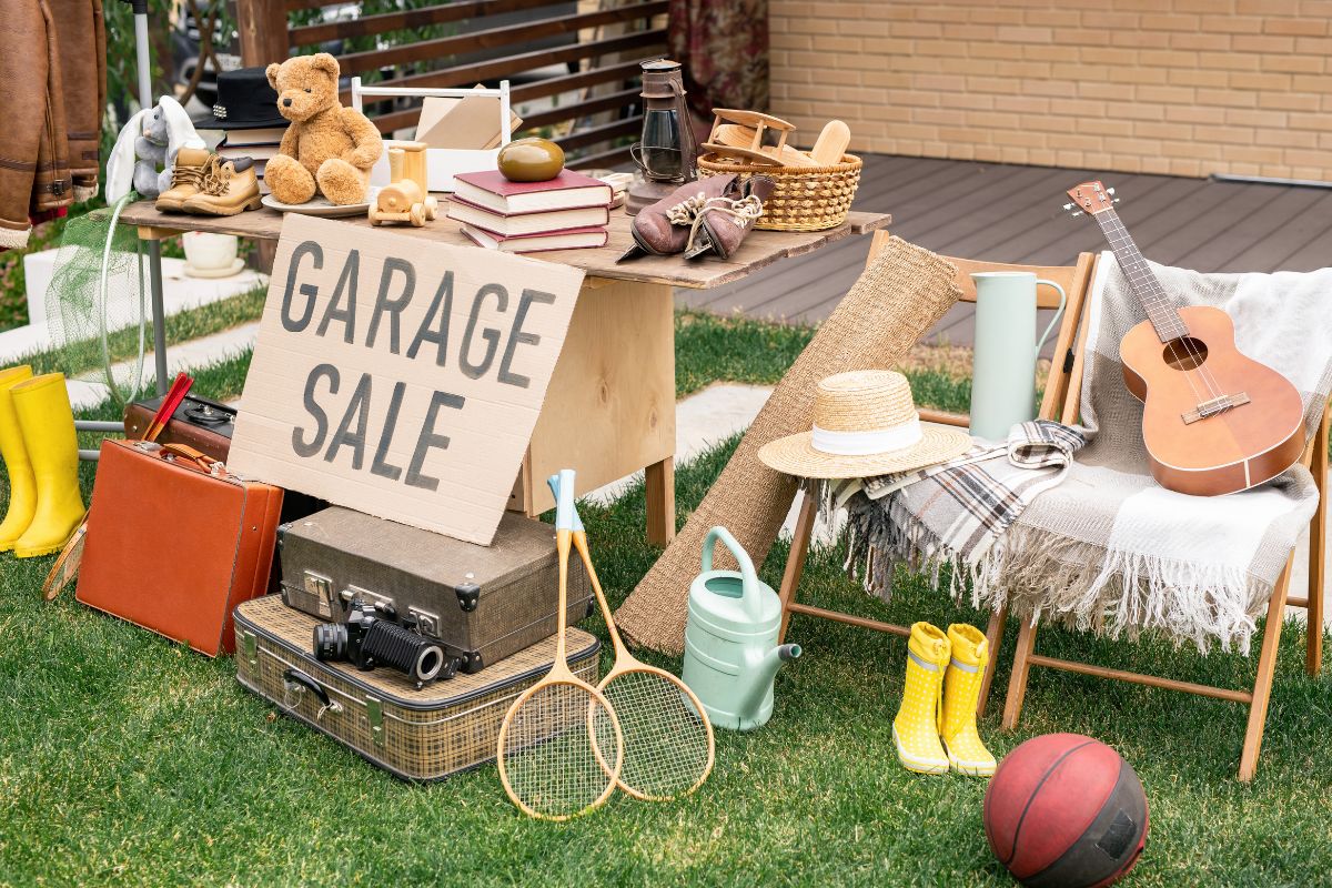 The picture shows a guitar, book, boots, a teddy bear, cases, and other stuff on the table and chairs referring to selling unused items as one of the fastest ways to boost your savings without changing your budget.
