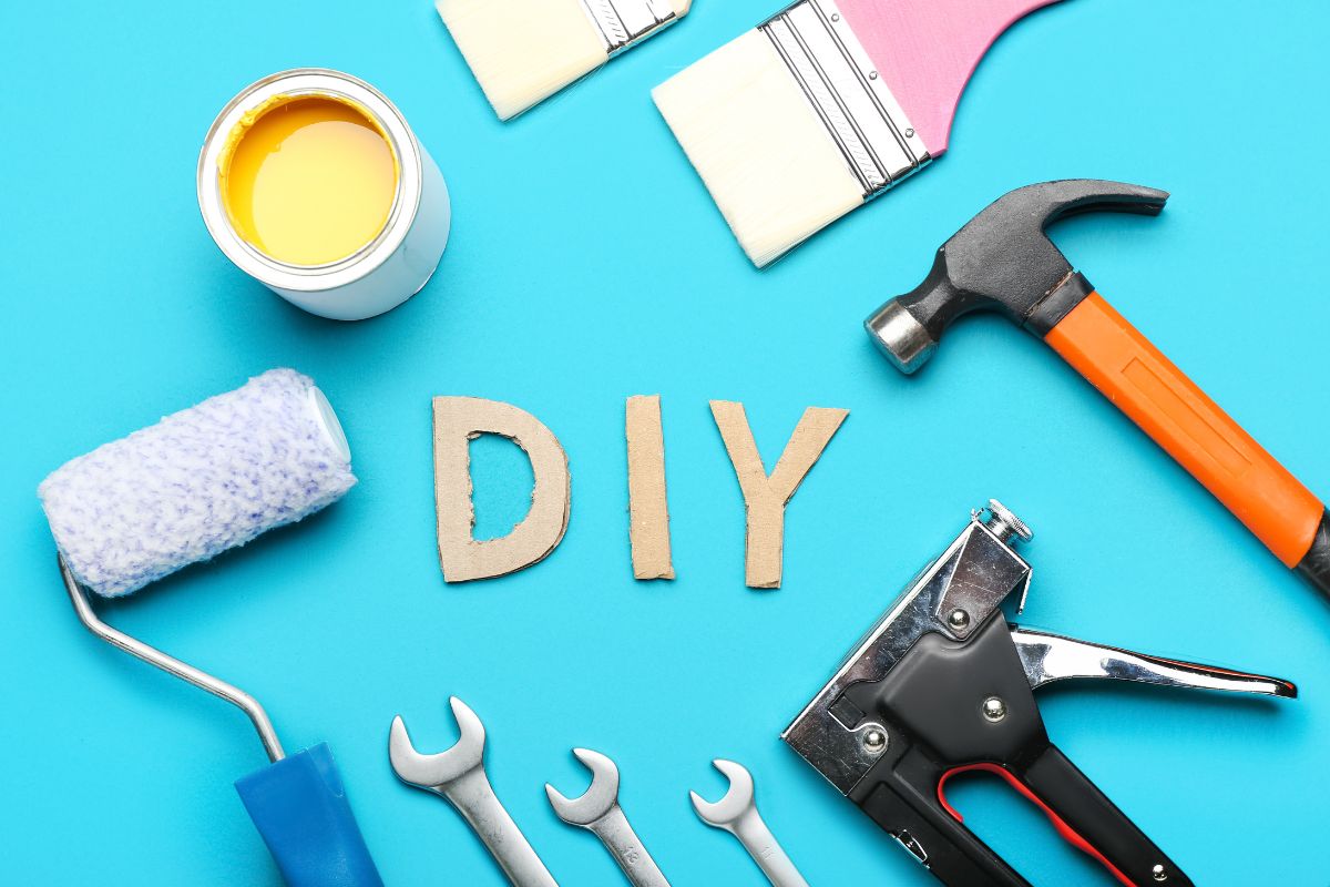 The picture tells about paint brushes, a hammer, paint, a stapler, metals, and letters referring to DIY whenever possible can save a lot of money.