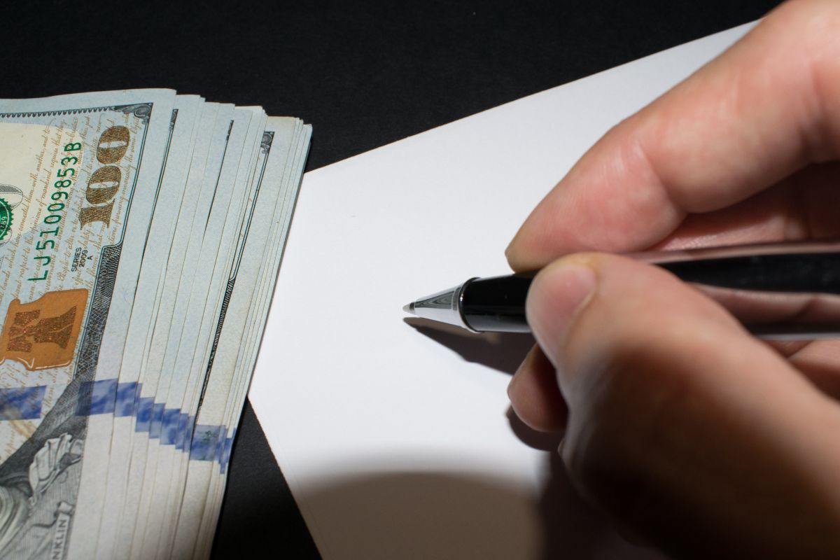 The photo of a money and a man's hand writing money on a paper.