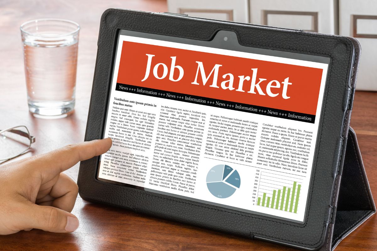 The image of a woman's hand using a tablet with a job market display.