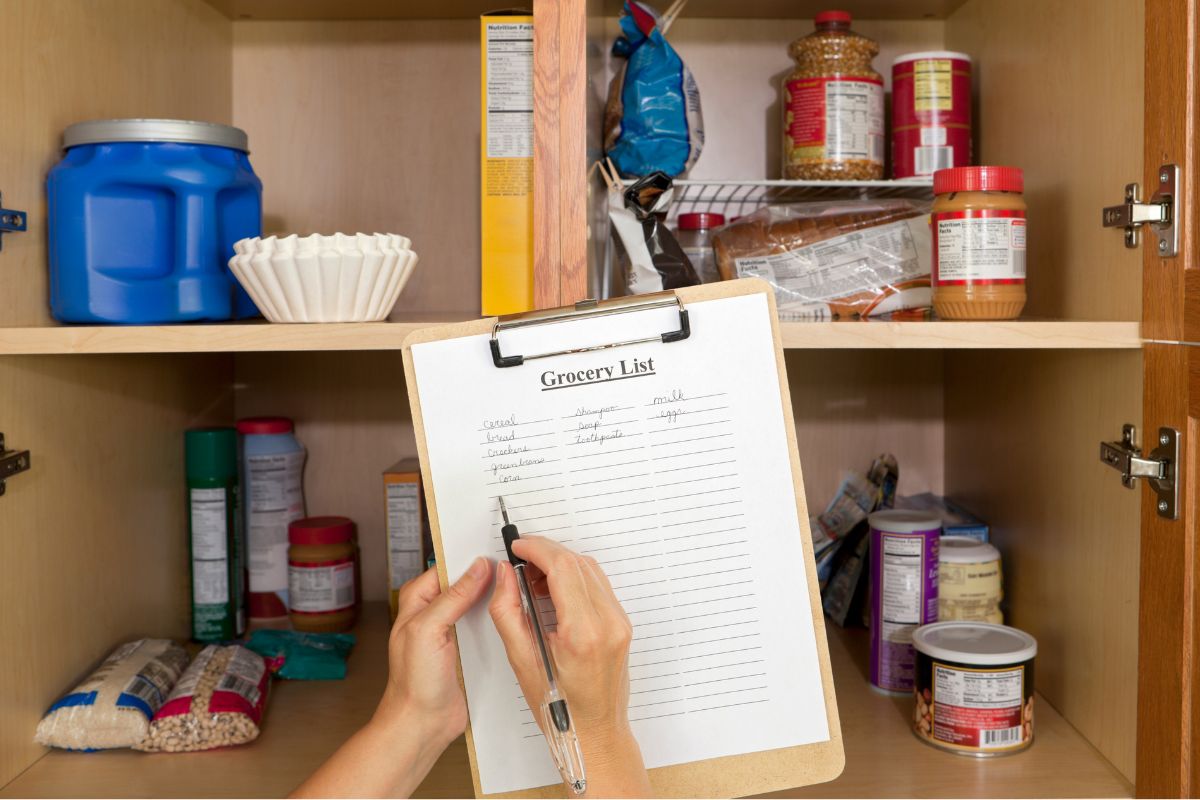 An image of a woman's hand making a grocery list.