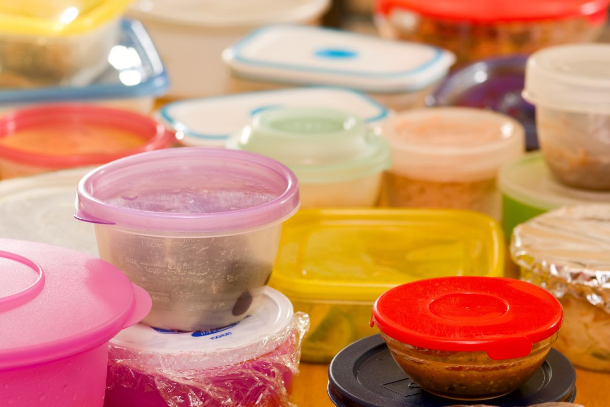 The image shows containers with leftover foods on the table referring to making a weekly leftover night reduces grocery costs by making sure every meal is eaten.